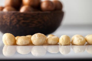 Bowl of Macadamia nuts, with shelled nuts in foreground